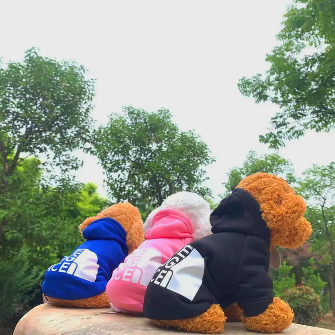 three dogs sitting in a park with the dog face hoodies on